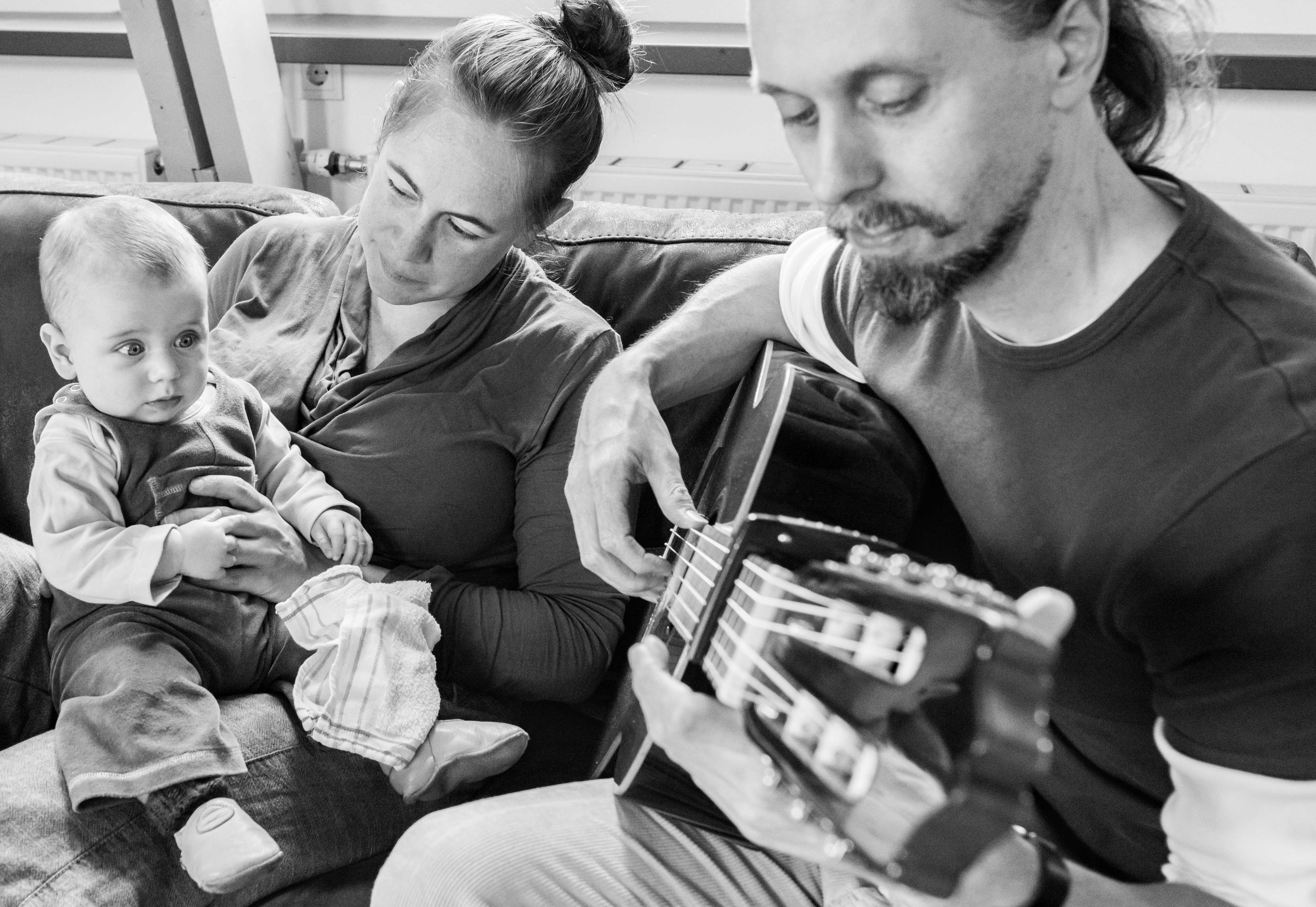 Vader speelt gitaar terwijl moeder en kind luisteren Jasja de Wit Fotografie