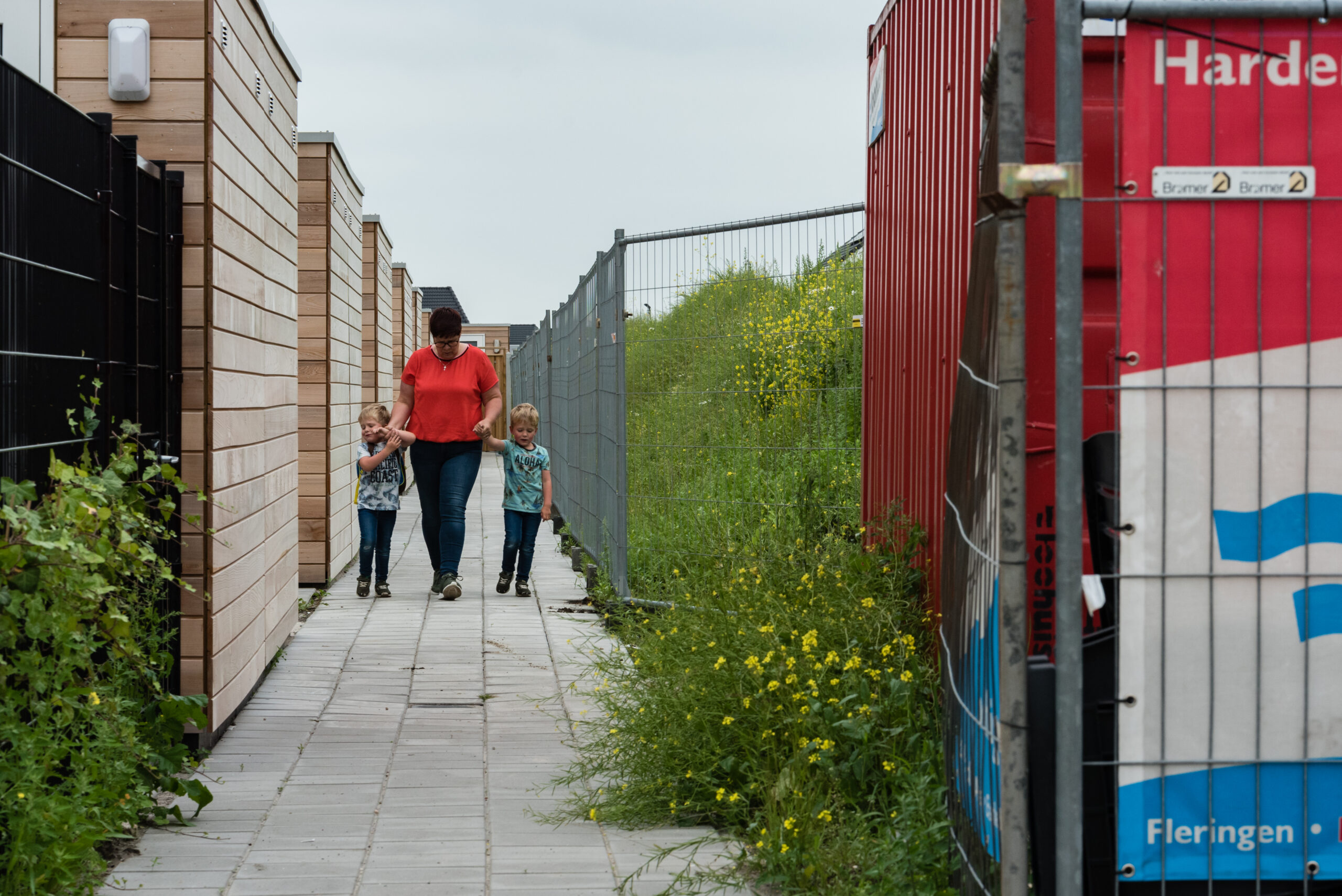 Moeder neemt kinderen aan de hand mee door de nieuwe steeg