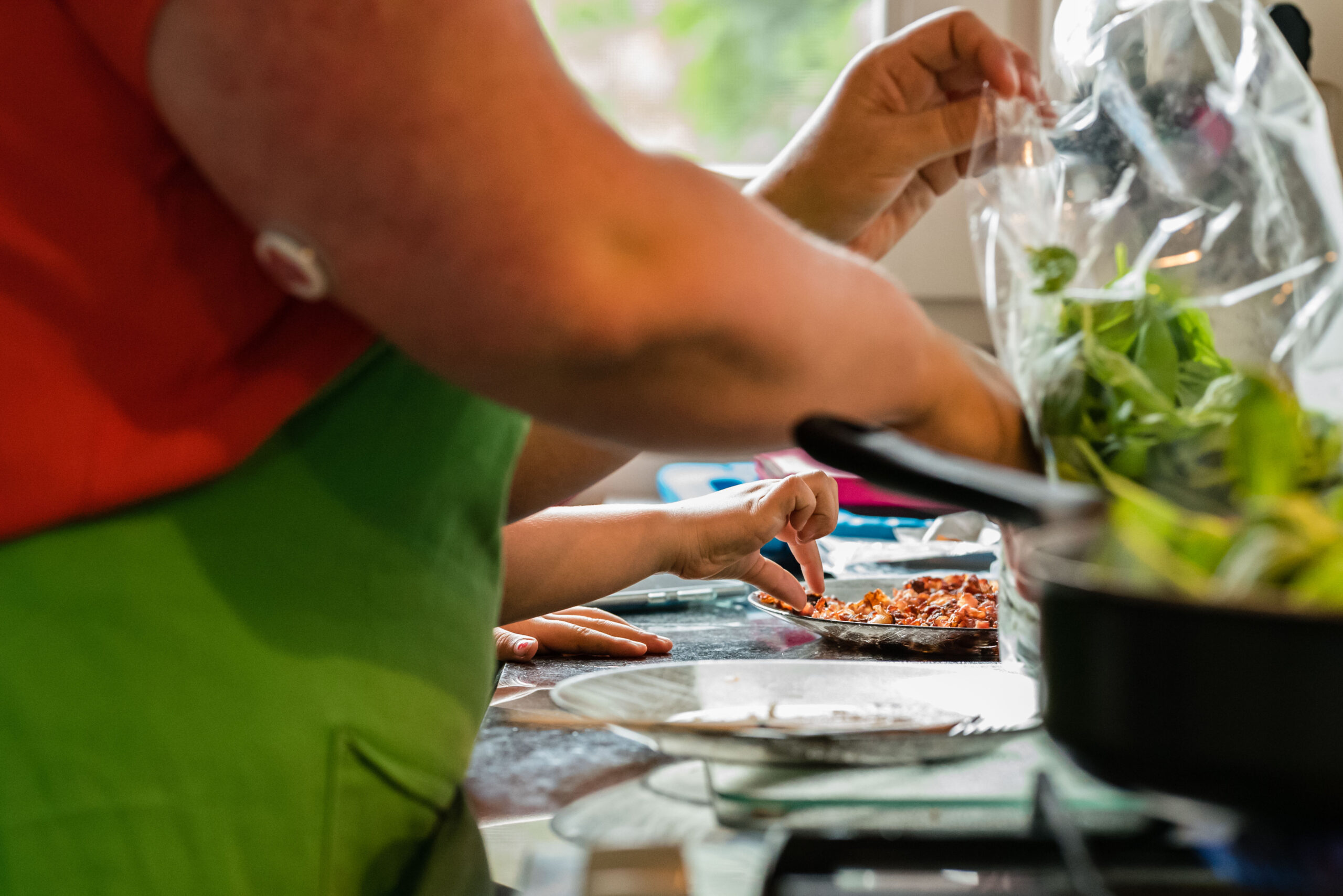 Meisje pikt pasgemakken spekjes van een bord tijdens het koken